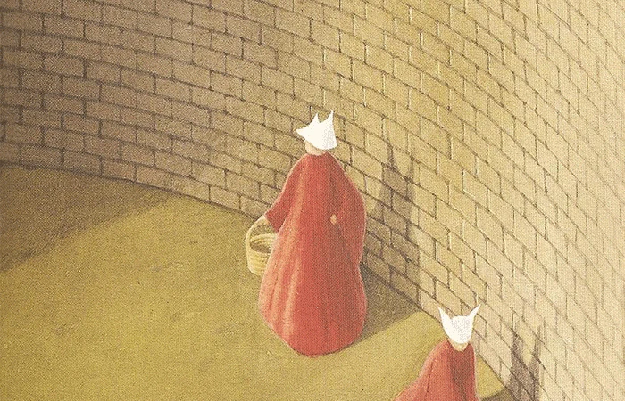 detail from the cover of Margaret Atwood's The Handmaid's Tale: two red robed figures with white whipples stand against a curving brick wall.